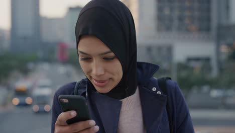 Retrato-Hermosa-Joven-Musulmana-Usando-Un-Teléfono-Inteligente-Disfrutando-Navegando-Mensajes-Leyendo-Mensajes-De-Texto-En-Línea-Usando-Velo-Hijab-En-La-Ciudad-Al-Atardecer-Mujer-Independiente