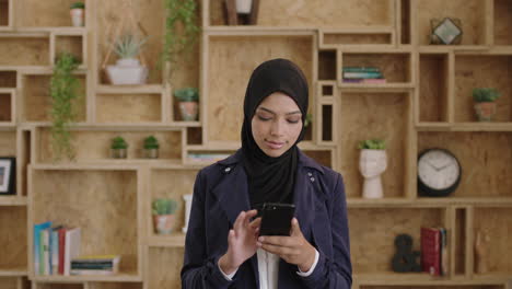 Retrato-De-Una-Joven-Mujer-De-Negocios-Musulmana-Que-Usa-Velo-Hijab-Enviando-Mensajes-De-Texto-Navegando-Usando-Un-Teléfono-Inteligente-Sonriendo-Feliz