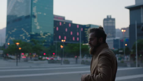 portrait-of-young-hipster-man-with-beard-looking-pensive-thinking-in-evening-urban-city-background-waiting-commuting-wearing-coat