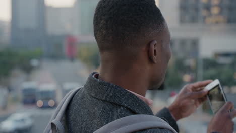 portrait-attractive-young-african-american-man-using-smartphone-taking-photos-of-busy-city-at-sunset-on-mobile-phone-camera-technology-slow-motion