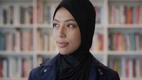 Porträt-Einer-Unabhängigen-Jungen-Muslimischen-Frau,-Die-Ruhig-Lächelt-Und-Den-Kopf-Dreht,-Der-Aus-Dem-Fenster-Schaut-Und-Ein-Hijab-Kopftuch-Im-Bücherregal-Hintergrund-In-Zeitlupe-Trägt