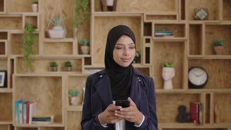 Retrato-De-Una-Joven-Y-Encantadora-Mujer-De-Negocios-Musulmana-Que-Usa-Un-Velo-Hijab-Enviando-Mensajes-De-Texto-Navegando-Usando-Un-Teléfono-Inteligente-Pensativo