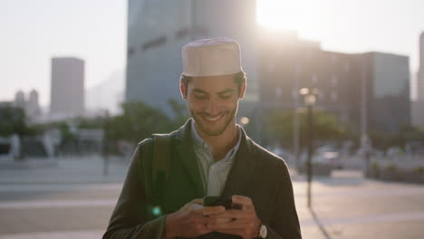 Nahaufnahme-Eines-Porträts-Eines-Attraktiven-Jungen-Muslimischen-Mannes,-Der-Bei-Sonnenuntergang-Auf-Der-Städtischen-Straße-SMS-Nachrichten-Schreibt-Und-Mit-Der-Mobilen-Messaging-App-Seines-Smartphones-Surft