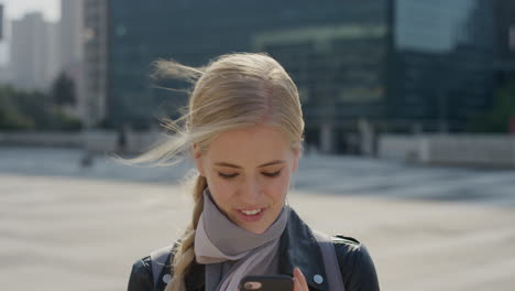 portrait-beautiful-young-blonde-woman-using-smartphone-enjoying-reading-text-messages-browsing-on-mobile-phone-in-sunny-urban-background-slow-motion