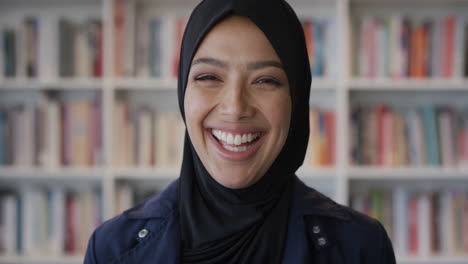 Retrato-Feliz-Joven-Musulmana-Riéndose-Disfrutando-De-Una-Educación-Exitosa-Mujer-Independiente-Usando-Un-Velo-Tradicional-Hijab-En-El-Fondo-De-Una-Estantería-En-Cámara-Lenta