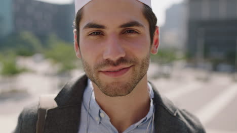 Retrato-De-Un-Atractivo-Joven-Musulmán-Del-Medio-Oriente-Sonriendo-Alegre-Disfrutando-De-La-Música-Se-Quita-Los-Auriculares-Mirando-La-Cámara-En-El-Fondo-Urbano-De-La-Ciudad