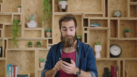 portrait-of-handsome-young-hipster-businessman-with-beautiful-beard-texting-browsing-using-smartphone