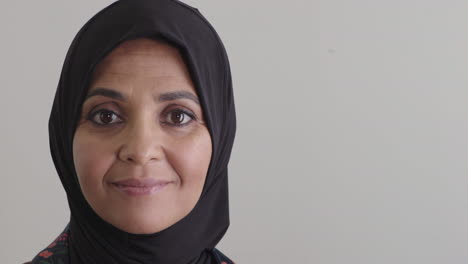 Fröhliche-Reife-Muslimische-Frau-Lächelt-Und-Genießt-Einen-Erfolgreichen-Lebensstil-Mit-Traditionellem-Hijab-Kopftuch-Auf-Leerem-Hintergrund,-Kopierraum-Aus-Nächster-Nähe