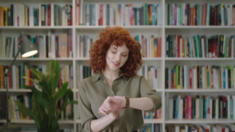 portrait-of-lovely-young-librarian-woman-standing-in-library-using-smart-watch-attractive-student-smiling-close-up-online-texting