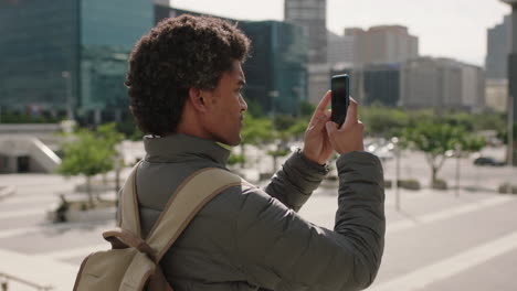 portrait-of-handsome-young-mixed-race-man-taking-photo-video-of-urban-city-using-smartphone-digital-app-sightseeing-travel