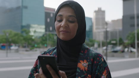 Nahaufnahme-Des-Porträts-Einer-Eleganten,-Reifen-Muslimischen-Frau,-Die-SMS-Schreibt-Und-Mit-Der-Smartphone-Social-Media-App-Surft-Und-Dabei-Im-Städtischen-Hintergrund-Chattet