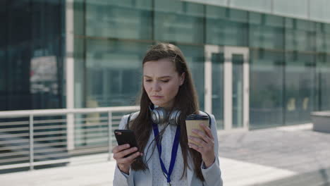 portrait-of-beautiful-young-woman-holding-coffee-and-using-smartphone-on-lunch-break-campus-intern-office-corporate-outdoors