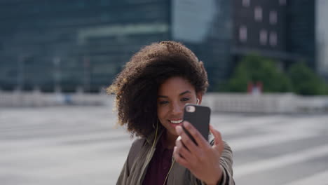 portrait-young-happy-african-american-woman-using-smartphone-taking-selfie-photo-in-city-student-enjoying-relaxed-urban-lifestyle-wearing-earphones-listening-to-music-trendy-afro-hairstyle
