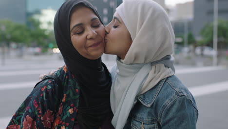 portrait-of-muslim-family-in-urban-city-daughter-kisses-mother-on-cheek-showing-affection-wearing-traditional-headscarf