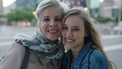 portrait-of-mother-and-daughter-embrace-looking-at-camera-smiling-happy-stylish-independent-women-in-urban-city-background