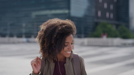 portrait-young-happy-african-american-woman-student-wearing-earphones-listening-to-music-dancing-enjoying-successful-urban-lifestyle-lively-black-female-student-afro-hairstyle-slow-motion