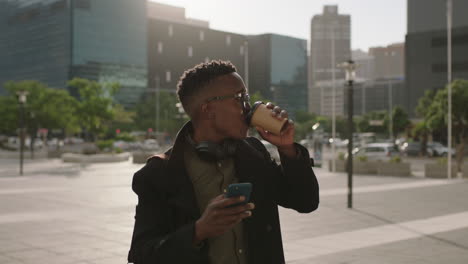 Retrato-De-Un-Joven-Estudiante-Afroamericano-De-Moda-Bebiendo-Café-En-La-Ciudad-Relajado-Usando-Gafas