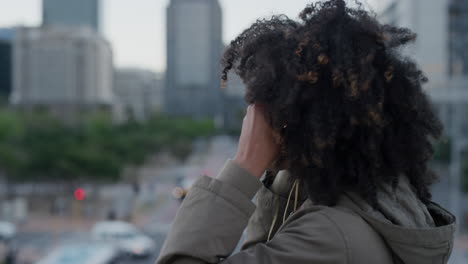 Porträt-Einer-Jungen-Afroamerikanischen-Frau,-Die-Kopfhörer-Aufsetzt-Und-In-Der-Stadt-Musik-Hört-Und-Einen-Entspannten-Urbanen-Lebensstil-In-Zeitlupe-Von-Der-Seite-Genießt