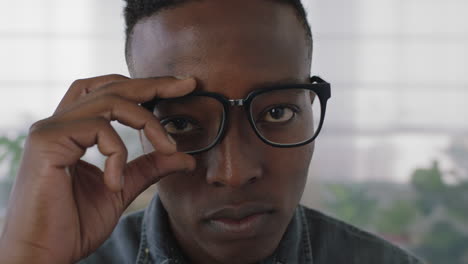 Nahaufnahme-Porträt-Eines-Jungen-Afroamerikanischen-Praktikanten,-Der-Eine-Brille-Aufsetzt-Und-Ernst-In-Die-Kamera-Blickt