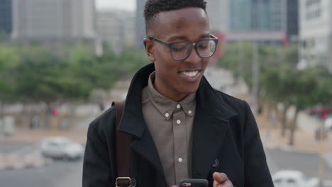 Retrato-Feliz-Estudiante-Afroamericano-Usando-Un-Teléfono-Inteligente-Tomando-Fotos-En-La-Ciudad-Con-La-Cámara-Del-Teléfono-Móvil-Disfrutando-Compartiendo-Fotografía-De-Viajes-Hombre-Negro-De-Moda-Con-Gafas