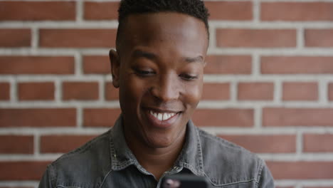 Porträt-Eines-Jungen-Afroamerikanischen-Studenten,-Der-Sein-Smartphone-Lächelt-Und-Das-SMS-Surfen-Genießt,-Indem-Er-Online-Surft-Und-SMS-Nachrichten-Auf-Dem-Mobiltelefon-Liest