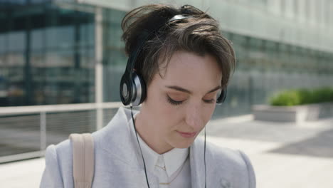 portrait-of-beautiful-young-business-woman-executive-puts-on-earphones-listening-to-music-texting-browsing-using-smartphone-enjoying-lunch-break