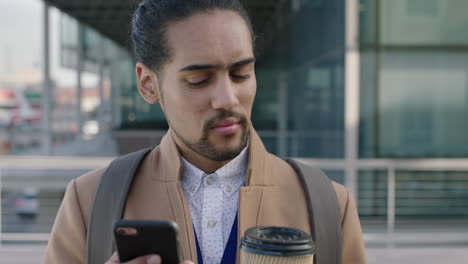 Porträt-Eines-Jungen-Hispanischen-Geschäftsmannes,-Der-Mit-Smartphone-Mobiltechnologie-In-Der-Stadt-Wartet-Und-SMS-Schreibt