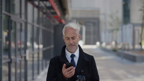Porträt-Eines-Erfolgreichen-Geschäftsmannes-Mittleren-Alters,-Der-Sein-Smartphone-In-Der-Stadt-Nutzt-Und-Dabei-Genießt,-SMS-Zu-Schreiben-Und-Nachrichten-Auf-Dem-Mobiltelefon-Zu-Durchsuchen.-Glücklicher-älterer-Unternehmer,-Der-Online-In-Zeitlupe-Kommuniziert
