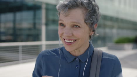 portrait-of-mature-successful-business-woman-smiling-happy-wearing-earphones-enjoying-listening-to-music-in-urban-city-background