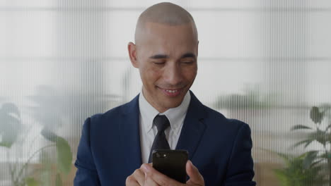 portrait-young-hispanic-businessman-using-smartphone-in-office-enjoying-texting-browsing-messages-sending-email-sms-on-mobile-phone-slow-motion