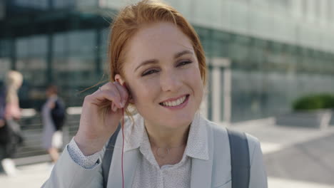 close-up-portrait-of-beautiful-red-head-business-woman-intern-smiling-happy-puts-on-earphones-enjoying-listening-to-music-on-lunch-break-in-city