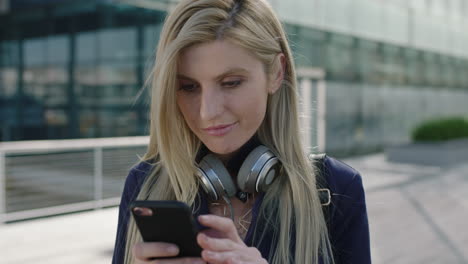 portrait-of-young-attractive-blonde-business-woman-intern-smiling-enjoying-texting-browsing-using-smartphone-social-media-app-in-city