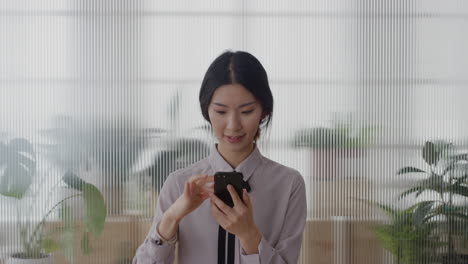 portrait-young-successful-asian-business-woman-intern-using-smartphone-enjoying-texting-browsing-online-messages-sending-email-sms-on-mobile-phone-in-office