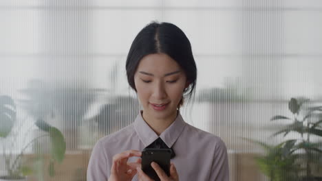 portrait-young-successful-asian-business-woman-intern-using-smartphone-enjoying-texting-browsing-online-messages-on-mobile-phone-laughing-funny-slow-motion