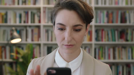 portrait-of-young-pensive-business-woman-in-library-office-texting-browsing-using-smartphone-brainstorming-creative-ideas-smiling-happy-confident