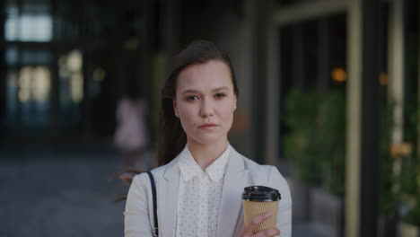 portrait-young-confident-business-woman-looking-serious-corporate-professional-holding-coffee-wind-blowing-hair-in-urban-outdoors-background-ambition-success