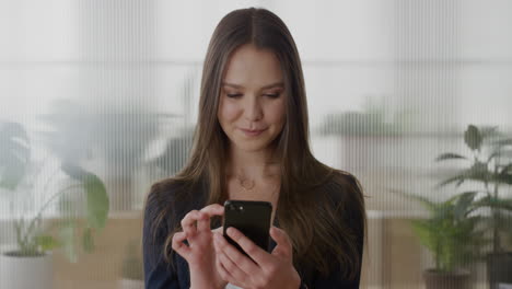 portrait-young-independent-business-woman-executive-using-smartphone-enjoying-texting-browsing-online-messages-sending-email-sms-on-mobile-phone-in-office