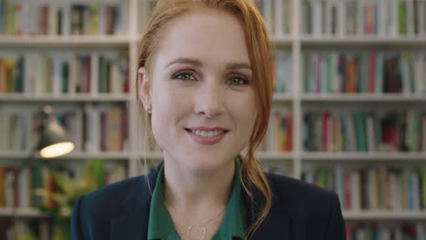 portrait-of-attractive-young-red-head-business-woman-intern-smiling-happy-enjoying-professional-career-opportunity-in-library-background