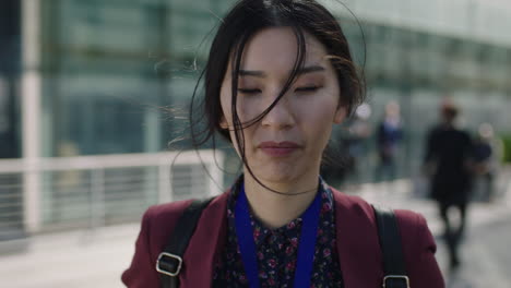 close-up-portrait-of-young-asian-business-woman-looking-to-camera-hair-blowing-in-wind