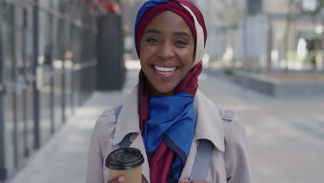 Porträt-Einer-Jungen-Unabhängigen-Afroamerikanischen-Geschäftsfrau,-Die-Lacht-Und-Den-Entspannten-Urbanen-Lebensstil-Genießt.-Schöne-Schwarze-Muslimische-Frau-Mit-Traditionellem-Hijab-Kopftuch-In-Der-Stadt,-Die-Kaffee-Hält