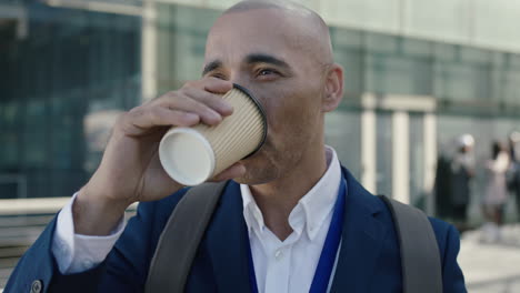 close-up-portrait-of-bald-hispanic-businessman-looking-facing-camera-drinking-coffee-corporate-office