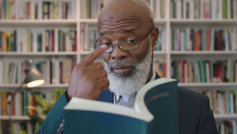 Porträt-Eines-Reifen-Afroamerikanischen-Geschäftsmannes-Mit-Bart-Und-Brille,-Der-Im-Bibliotheksstudium-Ein-Lesebuch-Recherchiert