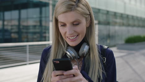portrait-of-young-lively-blonde-business-woman-intern-smiling-enjoying-texting-browsing-using-smartphone-social-media-app-in-city