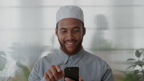 Porträt-Eines-Jungen-Muslimischen-Geschäftsmannes,-Der-Sein-Smartphone-Im-Büro-Benutzt-Und-Spaß-Daran-Hat,-SMS-Zu-Schreiben,-Auf-Dem-Mobiltelefon-Zu-Surfen-Und-SMS-E-Mails-Zu-Senden,-Lächelnd,-Glücklich,-Zufrieden,-Zeitlupe,-Technologie,-Verbundenheit