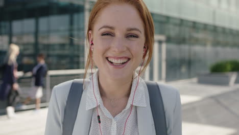 close-up-portrait-of-happy-red-head-business-woman-intern-wearing-earphones-listening-to-music-laughing-cheerful-enjoying-corporate-career-in-city