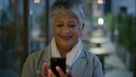 portrait-senior-indian-business-woman-using-smartphone-enjoying-texting-browsing-messages-reading-emails-in-city-evening-slow-motion-mobile-communication