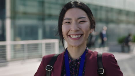 close-up-portrait-of-young-asian-student-woman-looking-to-camera-hair-blowing-in-wind-laughing