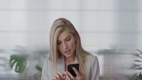 Porträt-Einer-Attraktiven-Jungen-Blonden-Geschäftsfrau,-Die-Im-Büro-Ihr-Smartphone-Nutzt-Und-Online-Nachrichten-Durchsucht-Und-SMS-Auf-Dem-Mobiltelefon-In-Zeitlupe-Sendet