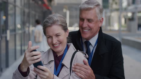 Porträt-Eines-Glücklichen-älteren-Paares,-Das-Lächelnd-Ein-Smartphone-Benutzt-Und-Ein-Selfie-Foto-In-Der-Stadt-Macht,-Das-Gemeinsam-Einen-Erfolgreichen-Urbanen-Lebensstil-In-Zeitlupe-Genießt