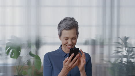 portrait-professional-senior-business-woman-using-smartphone-in-office-enjoying-texting-browsing-online-messages-sending-sms-on-mobile-phone-slow-motion